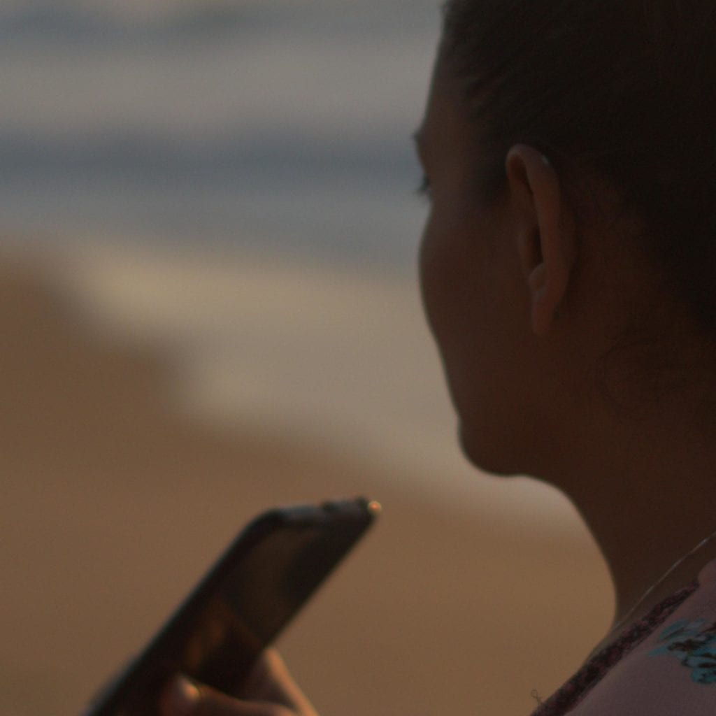 Miranda on the beach in California, speaking into her cell phone at sunset. This is how Miranda writes a lot of her letters to Adrian